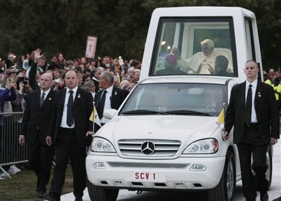 Pope Benedict XVI, followed by security guards, arrives aboard the popemobile in Hyde park to attend a vigil prayer in London.